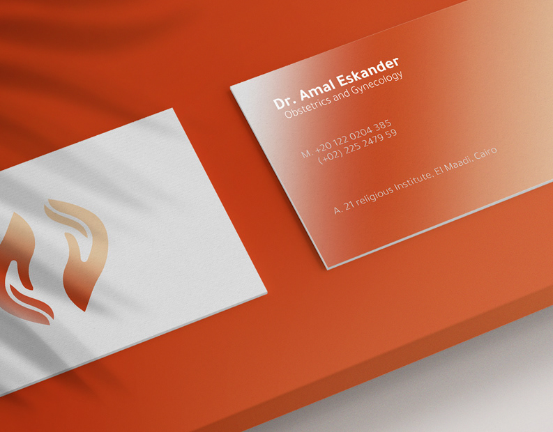 Dr. Amal Eskander business cards in white and burnt orange gradient, showing the two-hands logo and name