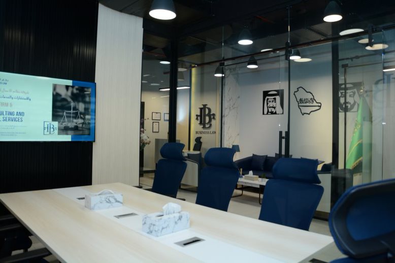 Business Law 2 Business Law meeting room with blue chairs, a screen and glass-walled offices