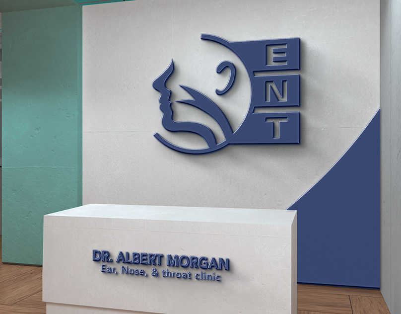 Dr. Albert Morgan ENT clinic logo as navy 3D signage on a reception wall above a branded front desk